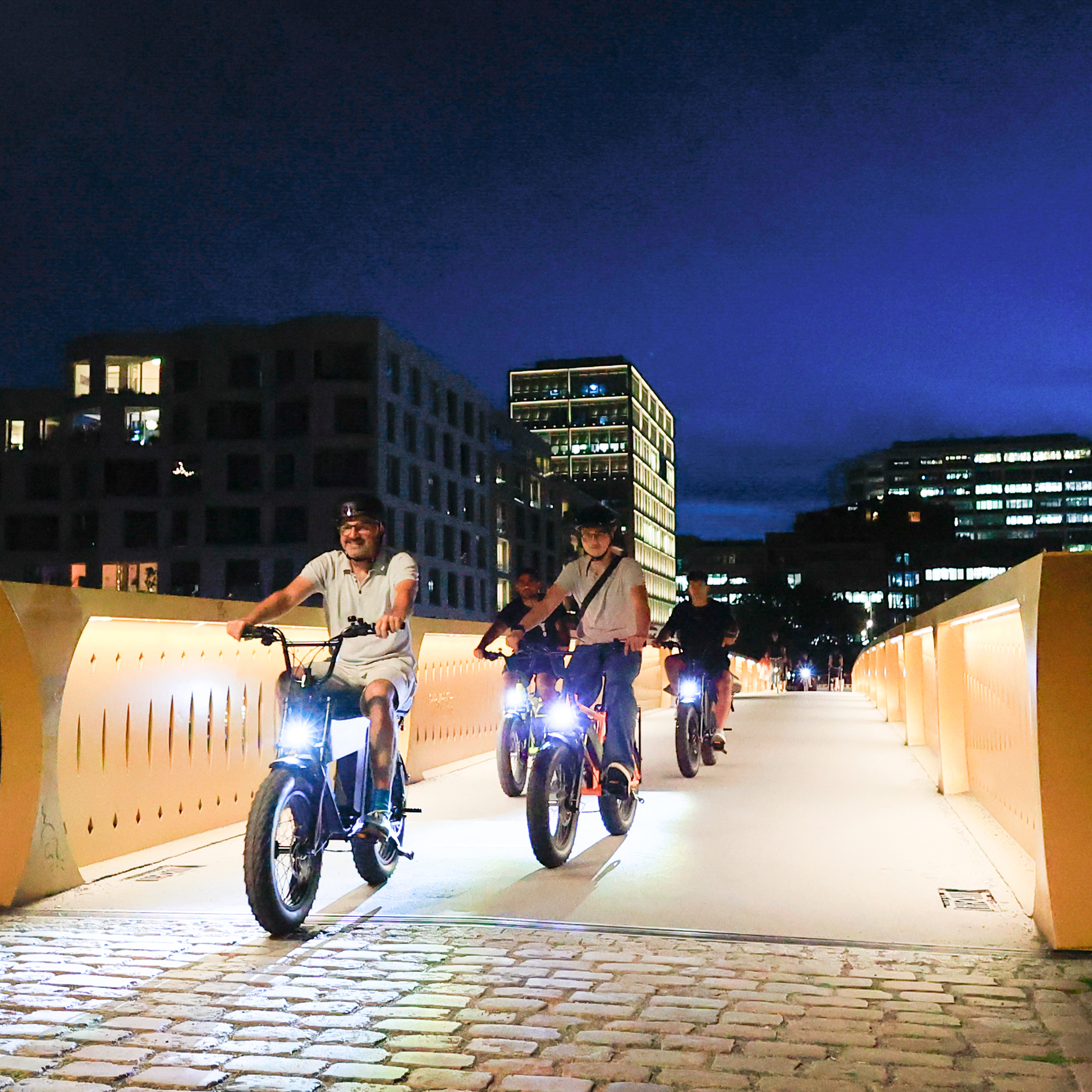 3 E-Cruiser fahren in der Dunkelheit über eine Brücke am Kanal in Berlin Mitte.